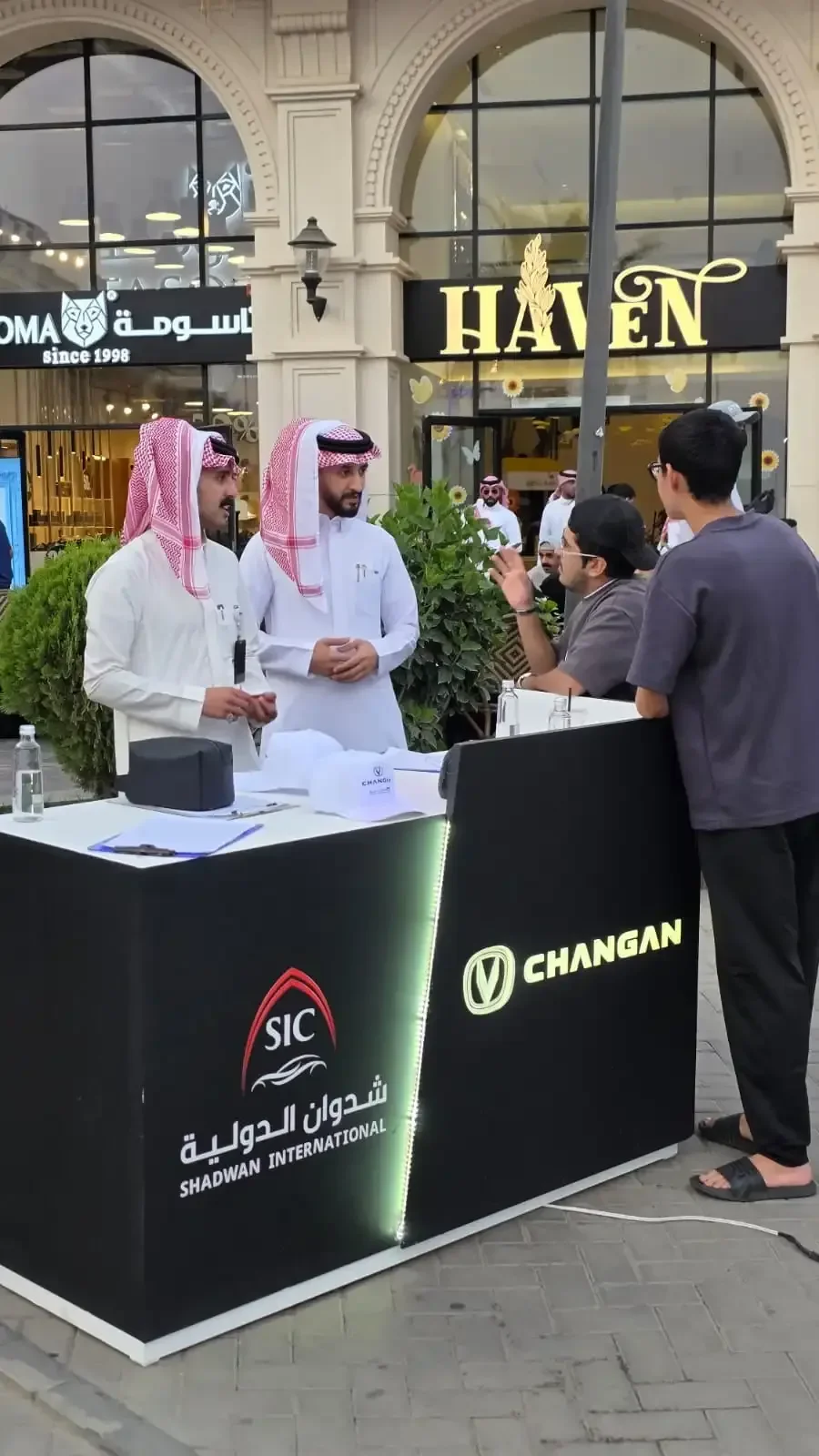 بوث تجربة قيادة شانجان بكاونتر أسود وشعار مضيء في فعالية الباحة 2026 — تصنيع زونكس